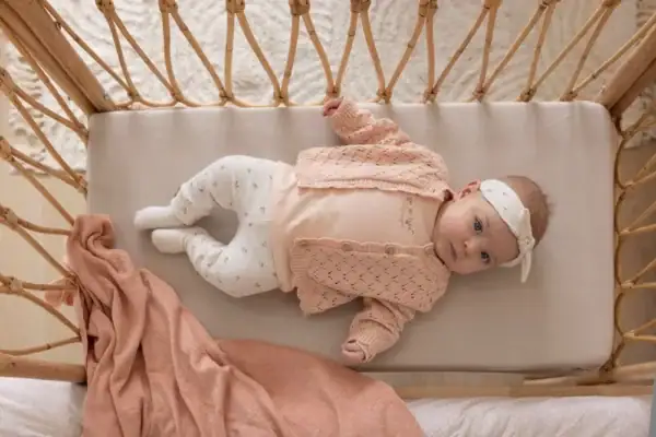 Baby met Feetje haarband op bed, offwhite melange, schattig en comfortabel.