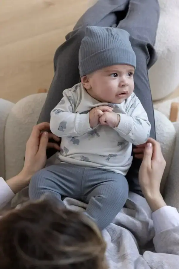 Baby met rib gebreid mutsje in blauw, comfortabel en schattig.